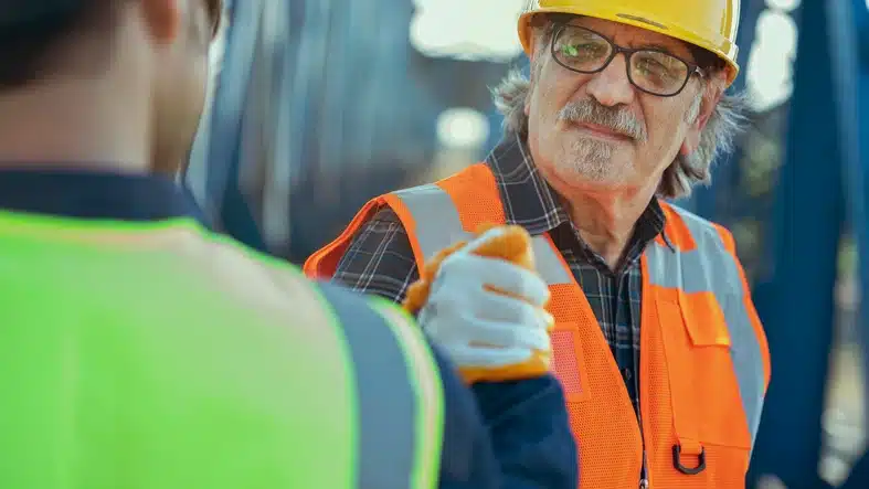 Workers in hard hats positively reacting to employee performance at worksite.