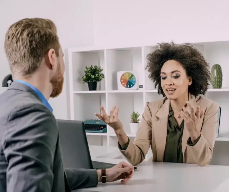 A man and women having a conversation in an office, managing difficult conversations and feedback