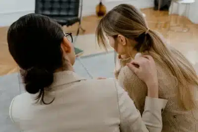 Two woman sitting together, on comforting the other who appears upset, emotional intelligence