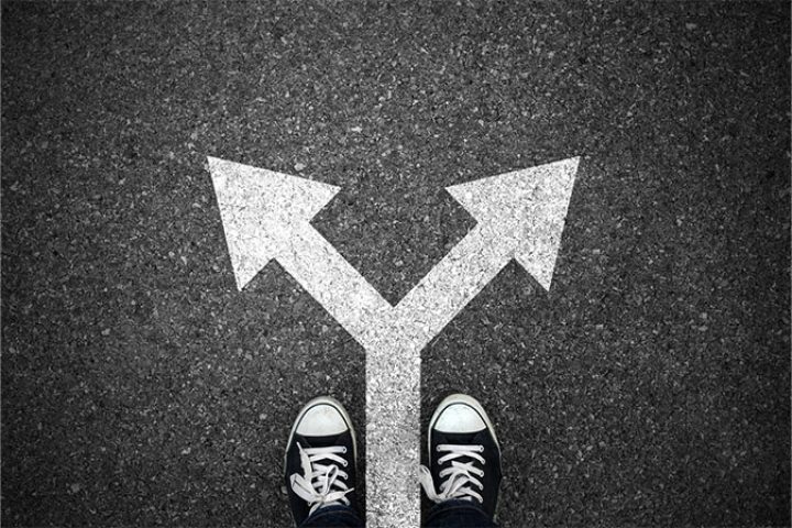 Person stares down at forked arrows representing career change.