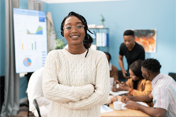Leader smiling as coworkers happily engage behind her.