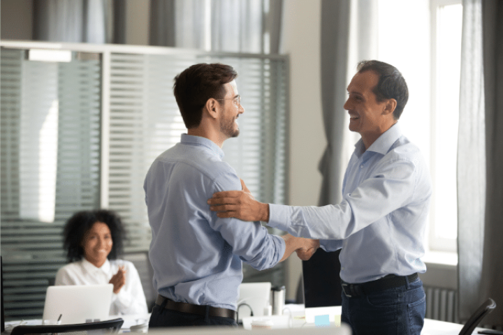 Men shaking hands as one has been promoted in leadership positions.